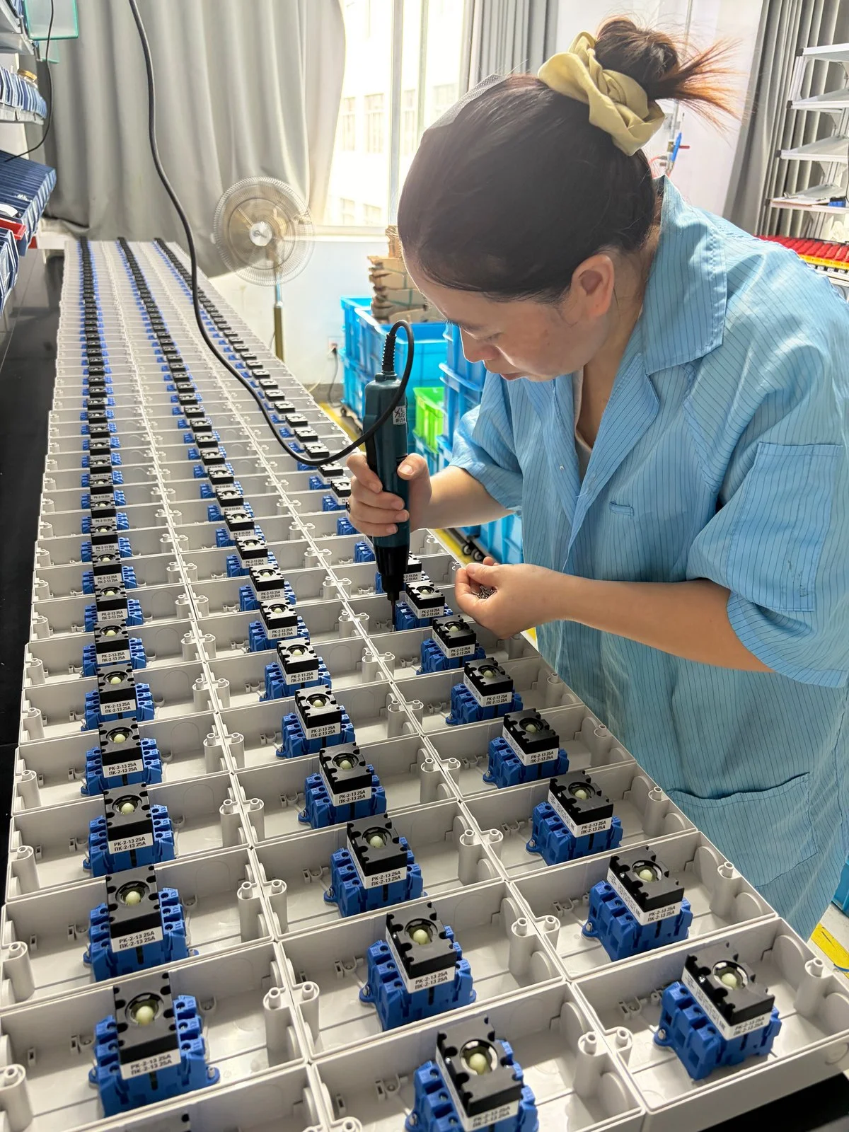 Operator assembling switch bodies with an electric screwdriver